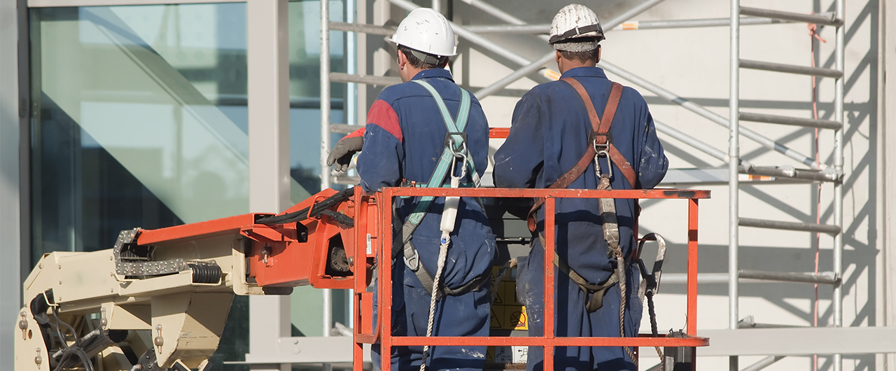 Workers wearing safety harnesses on an aerial access platform